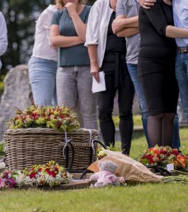 Kind-uitvaart-mandje-boven-graf-bloemen