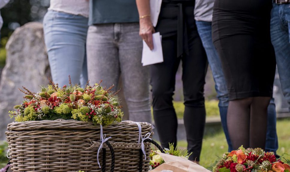 Kind-uitvaart-mandje-boven-graf-bloemen